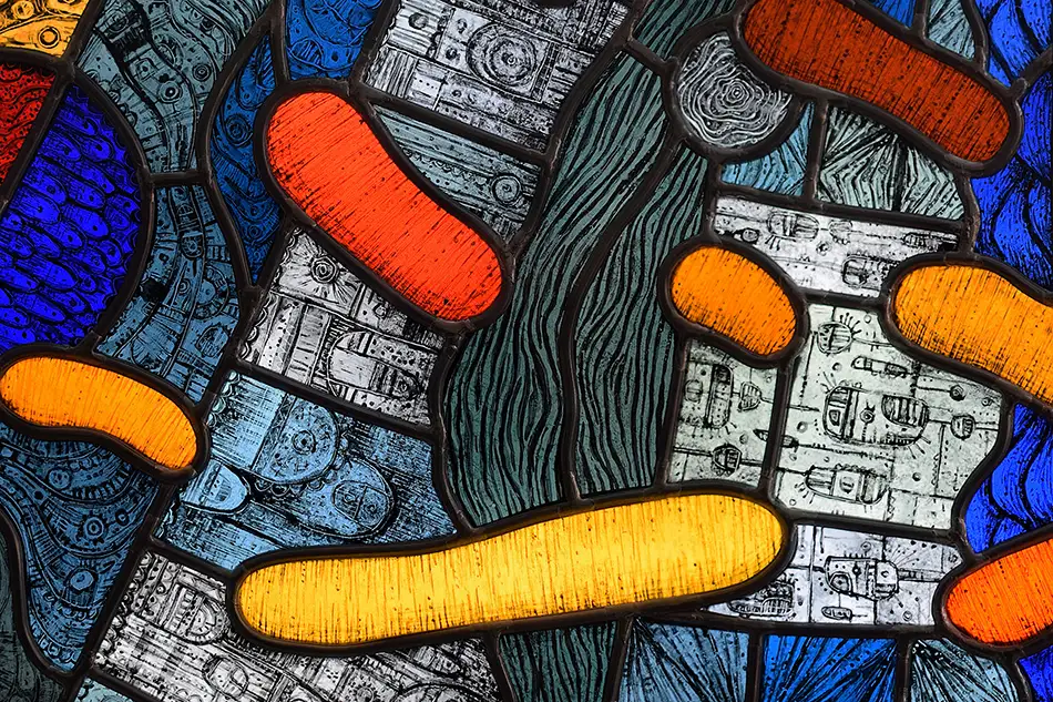 Detail of a free-hanging and illuminated stained glass window with detailed painting which is named Amoeba and hangs in a forest