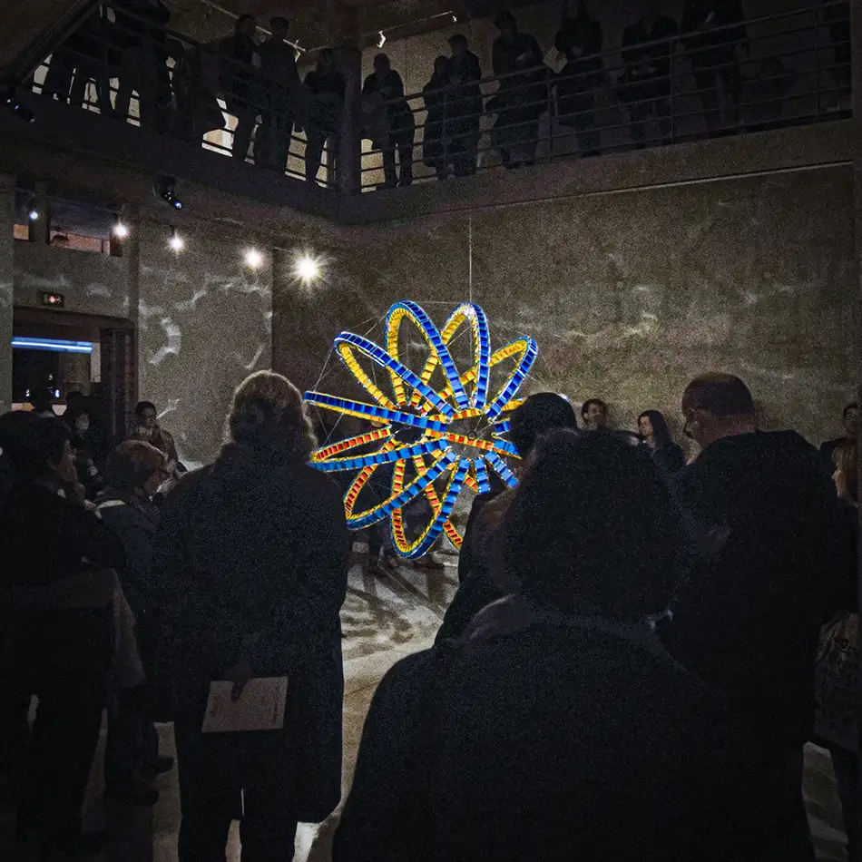Exhibition view with people of spherical art installation LudoModuL which plays with colour changes using different coloured wooden cubes