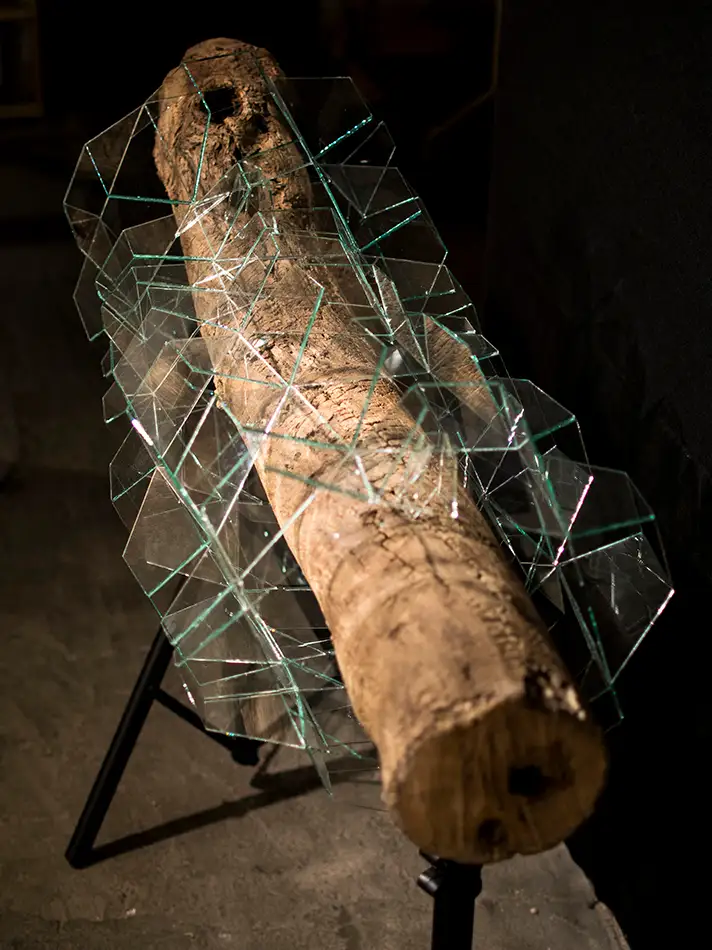geometrisches Glaskunst-Objekt das ein Stück Treibholz einkapselt