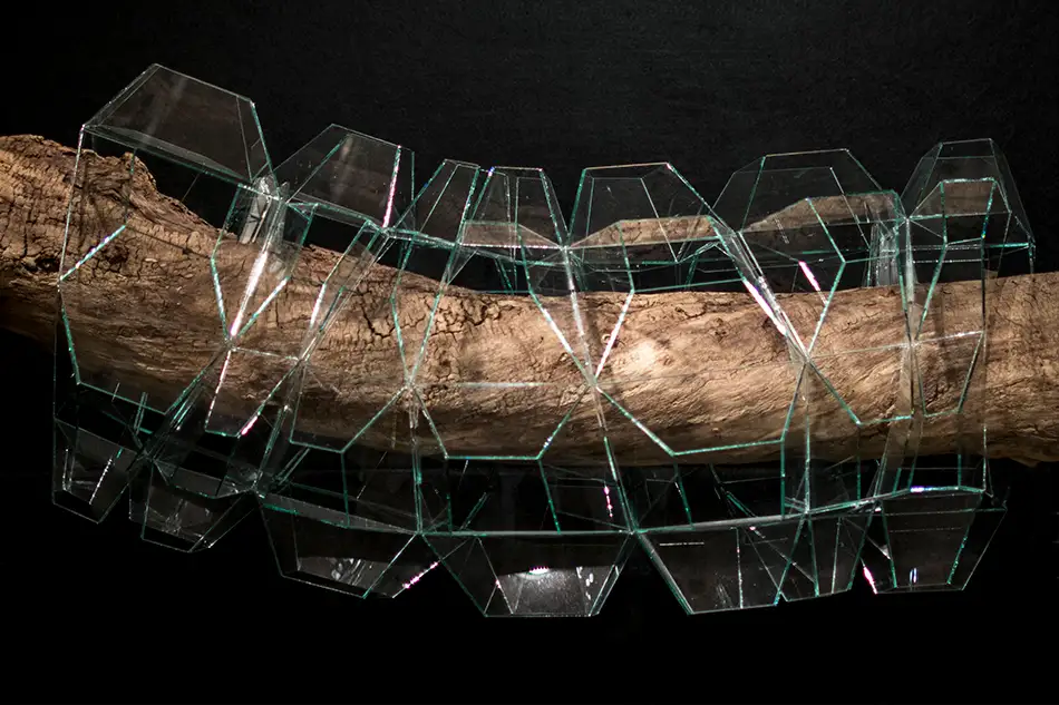 geometrisches Glaskunst-Objekt das ein Stück Treibholz einkapselt Seitenansicht