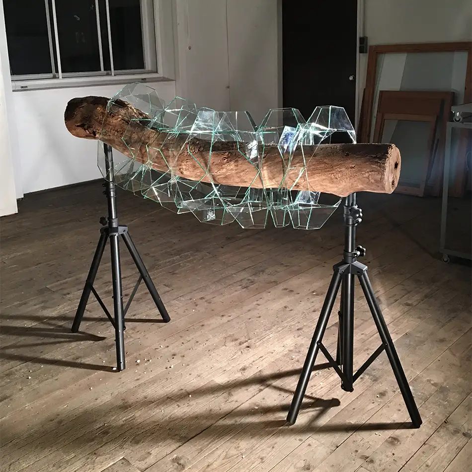 geometrisches Glaskunst-Objekt das ein Stück Treibholz einkapselt in der Werkstatt