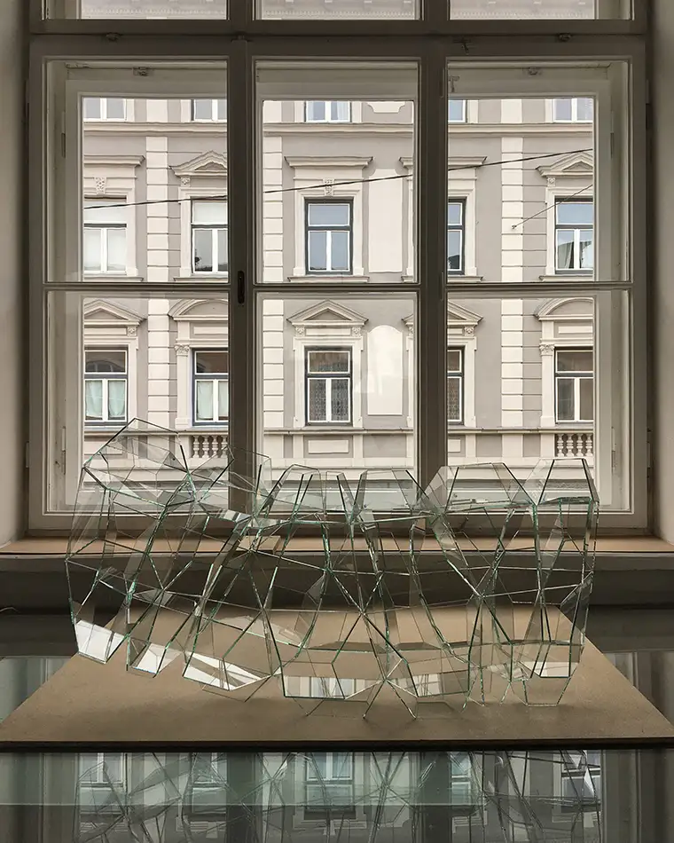 geometrischem Glaskunst-Objekt auf einem Tisch vor einer historischen Fassade