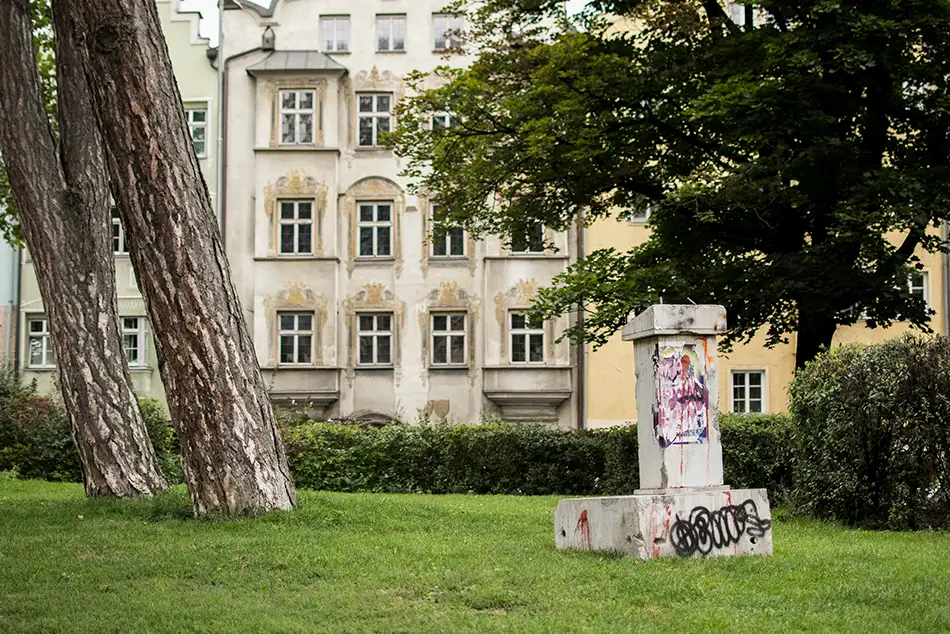 Heruntergekommenes Redepult aus Beton als Kunst im öffentlichen Raum mit Personen im Waltherpark Innsbruck