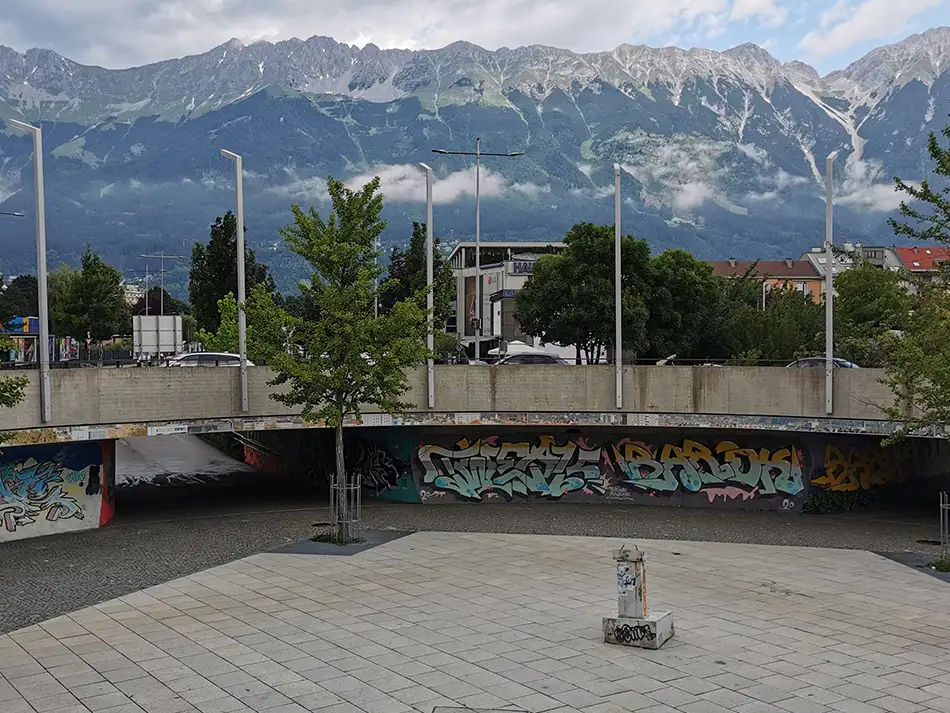 Heruntergekommenes Redepult aus Beton als Kunst im öffentlichen Raum mit Personen im Tivoli Kreisverkehr Innsbruck