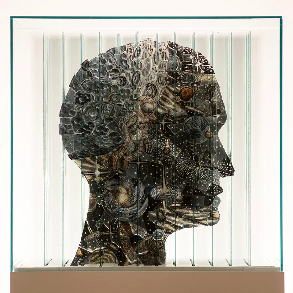 Anamorphic artwork - glass cube with four different images composed of image fragments - head profile with astronaut