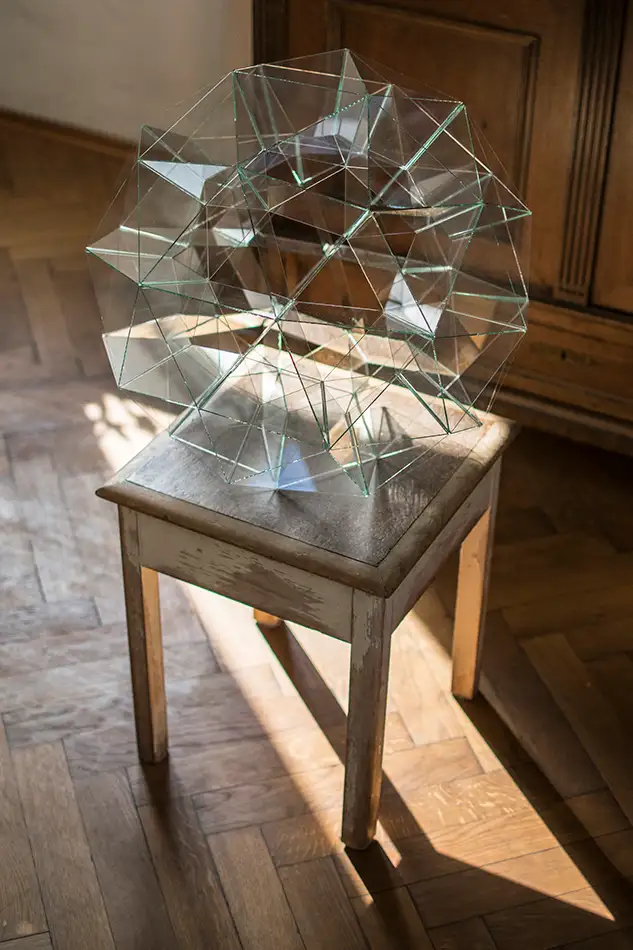 spherical glass sculpture that is geometrically based on the geodesic dome - lying on a chair