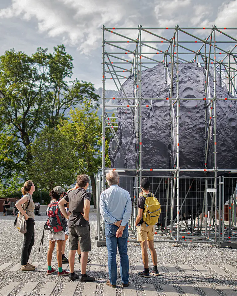 We Are the Asteroid - Art in public space - An asteroid in a scaffolding structure with people and a tree