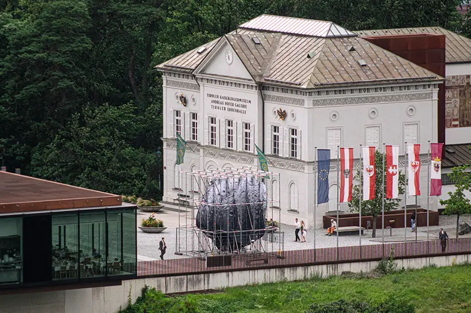 Public art installation called We Are the Asteroid, featuring an asteroid in a scaffolding structure on the square in front of the Tirol Panorama with the Kaiserjägermuseum in the background